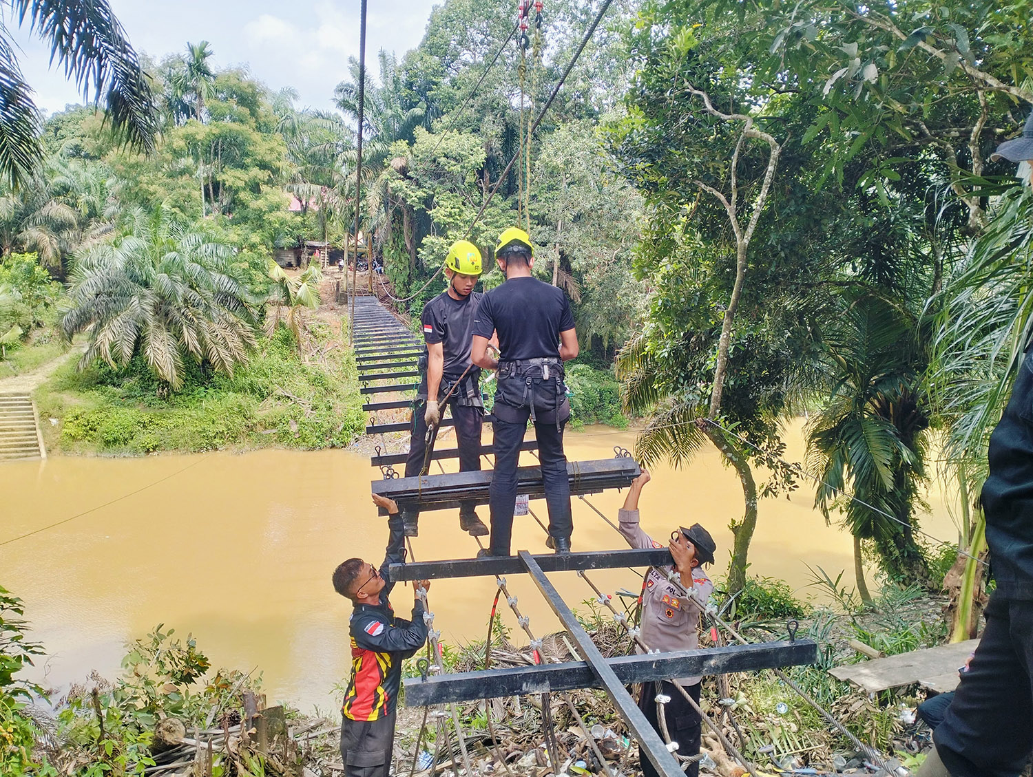 Personel Polres Kuansing menggesa pembangunan jembatan gantung Merah Putih di Desa Muara Tiu Makmur, Kecamatan Pucuk Rantau, Selasa (17/2/2026).