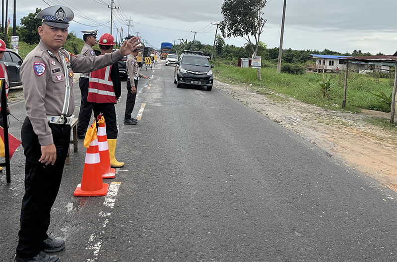 Personel Sat Lantas Polres Pelalawan melakukan pengaturan buka tutup Jalintim Km 75 dampak adanya pengerjaan penimbunan jalan, Kamis (19/2/2026).
