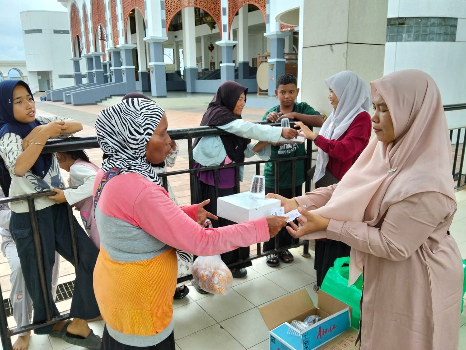 Pegawai Bagian Kesra Setdakab Rohul membagikan paket lengkap buka puasa kepada perwakilan kaum duafa di selasar Masjid Agung Islamic Center Rohul, Kamis (19/2/2026) petang.