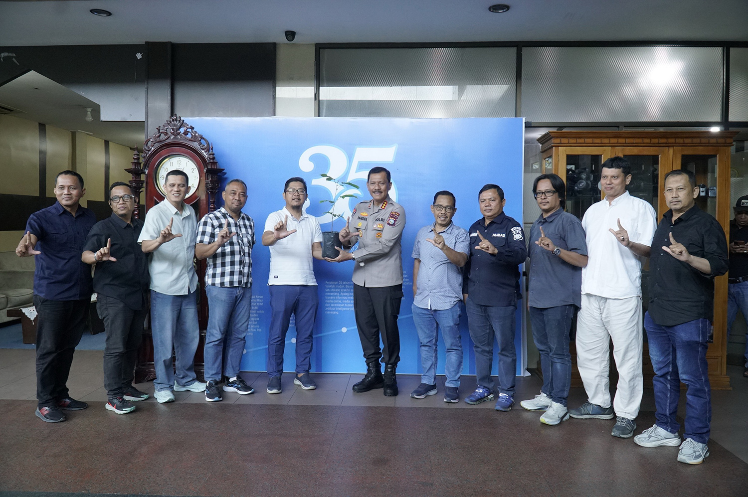 Kabid Humas Polda Riau Kombes Pol Zahwani Pandra Arsyad (tengah) menyerahkan bibit pohon kepada Direktur Utama Riau Pos Ahmad Dardiri (lima kiri) usai pertemuan silaturahmi, Kamis (19/2/2026).