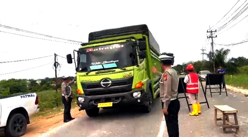Personel Satlantas Polres Pelalawan melakukan pengaturan lalu lintas di Jalintim Km 75 yang diberlakukan buka tutup jalan akibat adanya proyek penimbunan dan peninggian badan jalan, Jumat (20/2/2026).