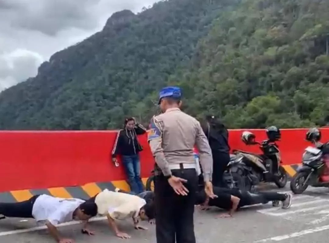 Petugas Satlantas Polres Limapuluh Kota menindak pengendara yang parkir sembarangan dengan sanksi push up saat operasi pengamanan arus mudik Ramadan 1447 H di Flyover Kelok Sembilan, Limapuluh Kota