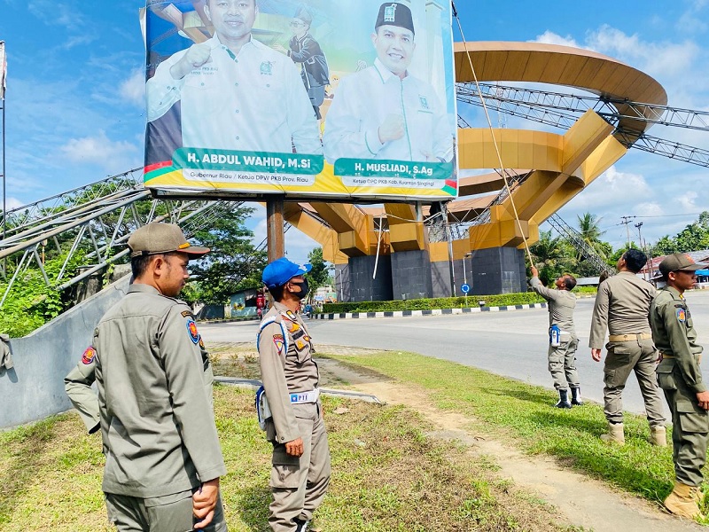 Personel Satpol PP-PKP Kuansing melakukan penurunan baliho Gubernur Riau H Abdul Wahid yang sudah kadaluwarsa, Jumat (20/2/2026) siang.