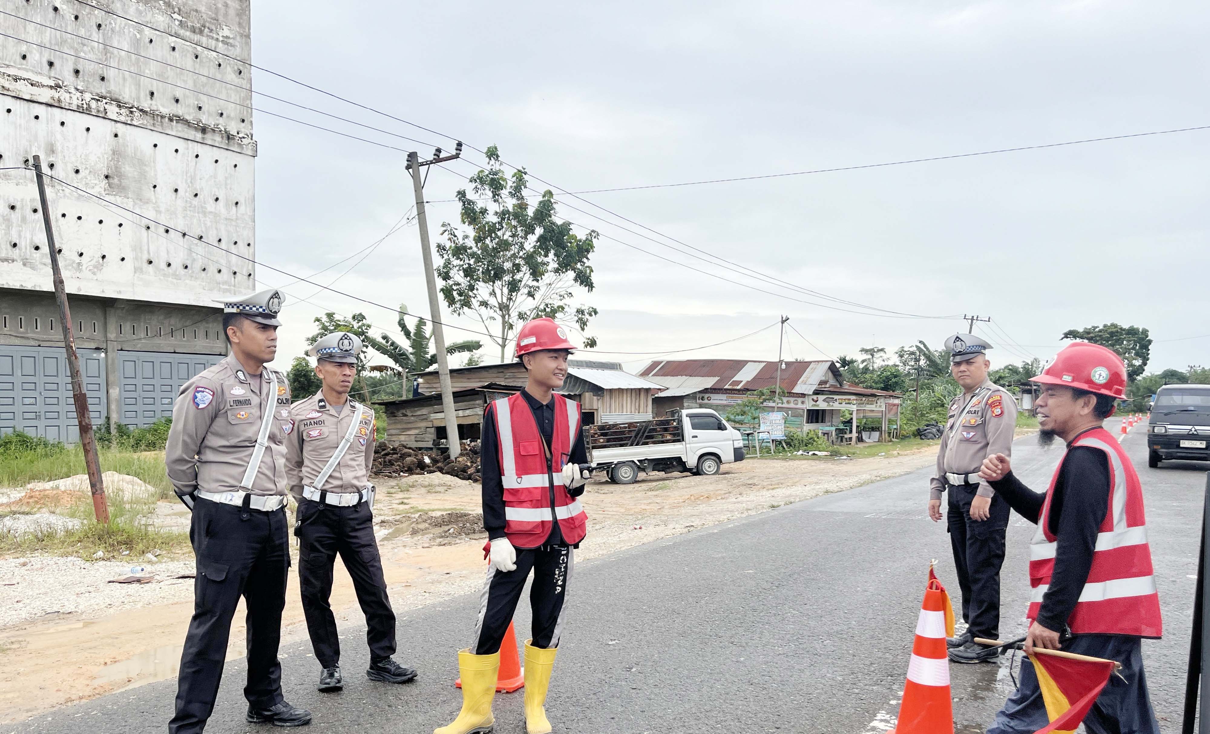 Personel Satlantas Polres Pelalawan melakukan pengaturan lalu lintas dengan sistem buka tutup di Jalintim km 75 yang masih normal, Sabtu (21/2/2026).