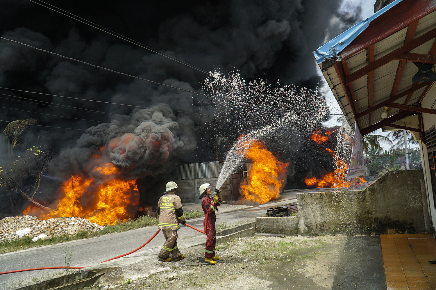  Petugas pemadam kebakaran berjibaku melakukan pemadamkan api yang membakar gudang diduga tempat penyimpanan solar di Jalan Sidodadi, Kecamatan Marpoyan Damai, Kota Pekanbaru, Ahad (22/2/2026) siang. 