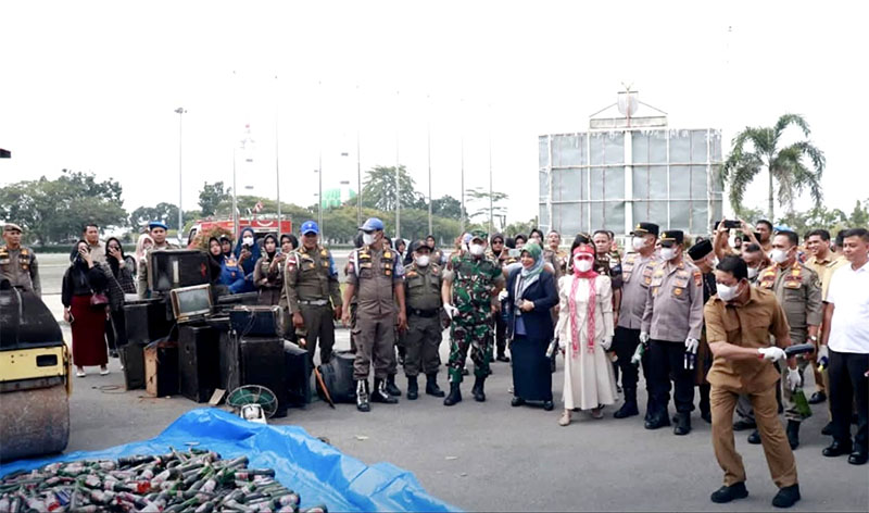 Wabup H Syafaruddin Poti melempar botol miras ke alat berat Bomag saat pemusnahan ratusan botol miras dan tuak hasil penegakan Perda Tahun 2025 di halaman kantor Bupati, Selasa (24/2/2026). 