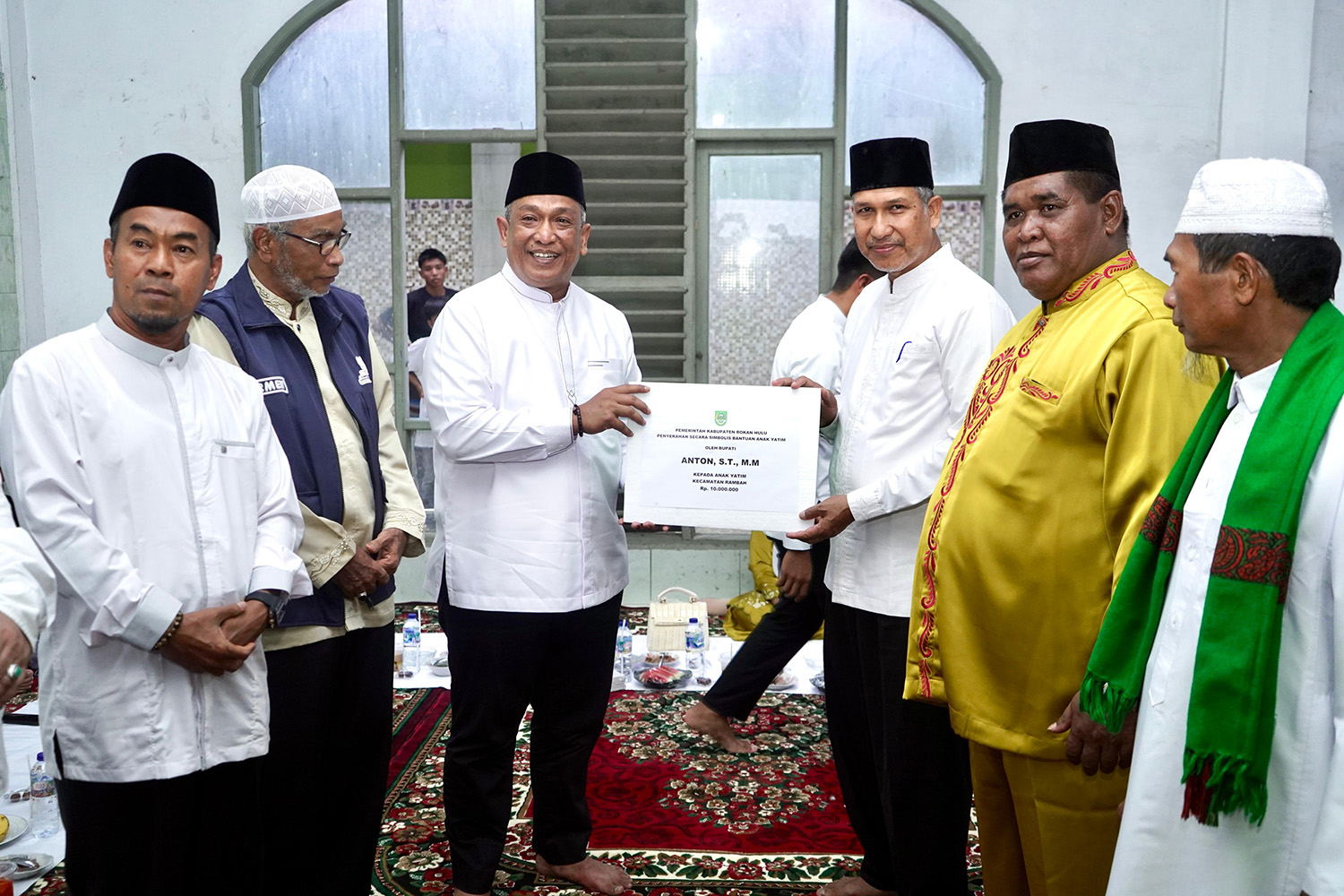 Bupati Rohul Anton ST MM menyerahkan bantuan santunan anak yatim piatu tingkat kecamatan kepada Camat Rambah Sulfan Alwi dalam kunjungan Safari Ramadan perdana di Masjid Jamiatul Mukarromah Desa Suka 