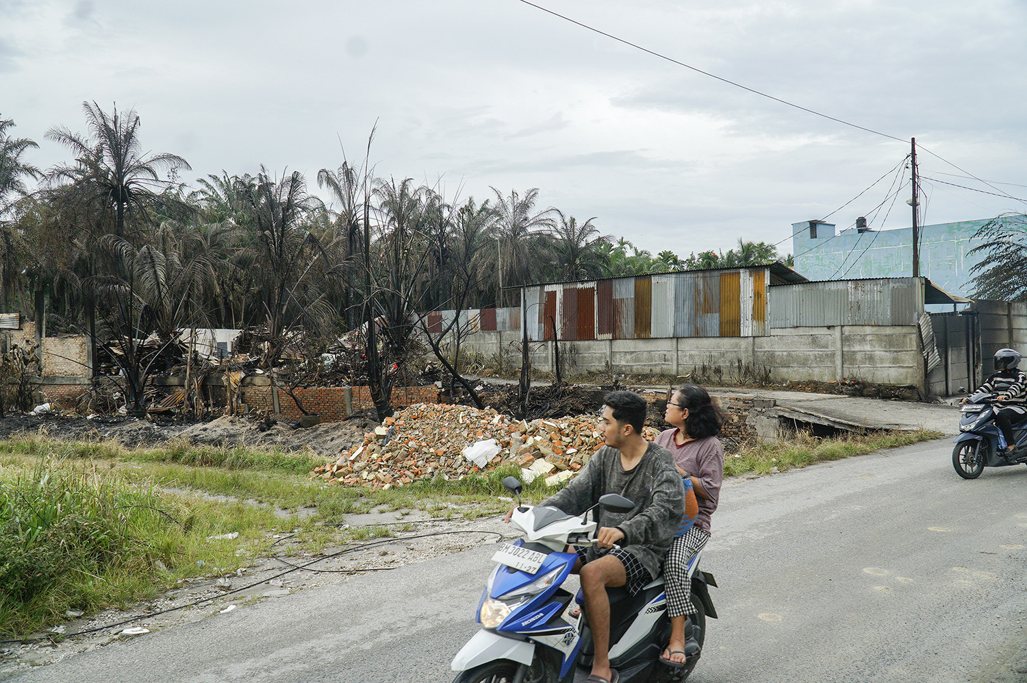 Warga melintas di lokasi bekas kebakaran yang merupakan gudang diduga tempat penyimpanan solar di Jalan Sidodadi, Marpoyan Damai, Pekanbaru, Senin (23/2/2026).