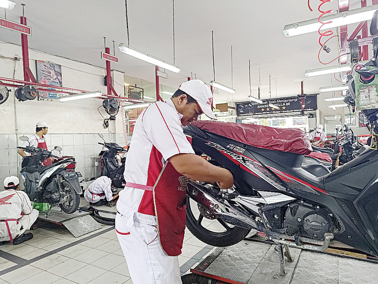 Seorang petugas melakukan servis motor pelanggan di salah satu bengkel resmi AHASS di Pekanbaru, Senin (23/2/2026). 