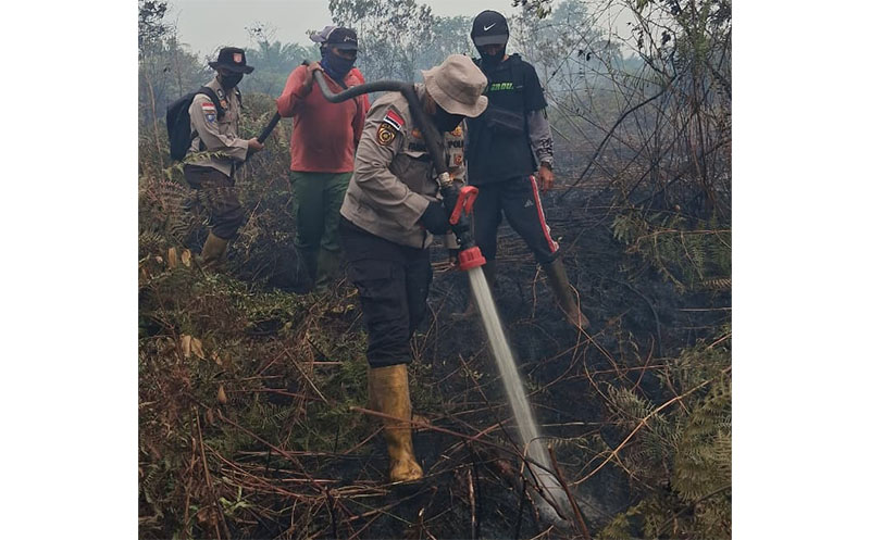 Kapolsek Rupat AKP Faisal melakukan pendinginan api karhutla di lahan masyarakat di Desa Sukarjo Mesim, Kecamatan Rupat, Bengkalis, Selasa (24/2/2026). 