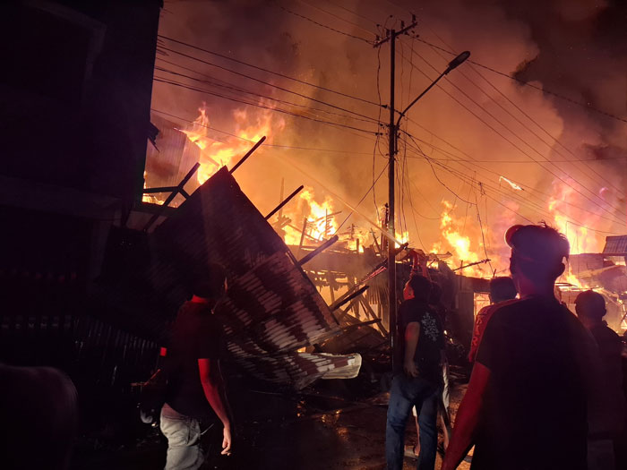 Petugas bersama warga berupaya memadamkan api yang membakar 16 pintu Ruko dan kios di komplek pasar Peranap Kecamatan Peranap, Selasa (24/2/2026).