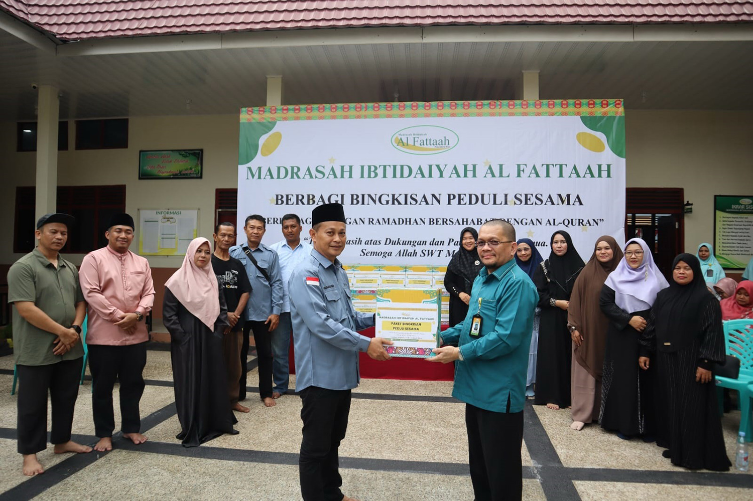 Kepala Madrasyah Ibtidaiyah Al Fattaah Pekanbaru H Roudhatul Firdaus LC MPd menyerahkan bingkisan peduli sesama warga yang diwakili oleh Ketua RW 06 Kelurahan Sekip Agus Faisal SpdI, belum lama ini. 