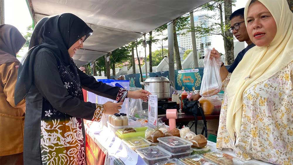 Pembeli di UMKM "Kampong Ramadan Kite" melakukan pembayaran menggunakan  Qris yang difasilitasi  Bank Riau Kepri Syariah