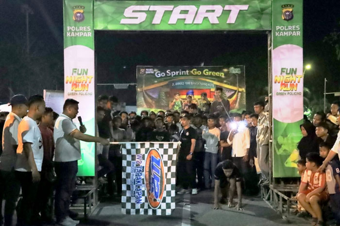 Kapolres Kampar AKBP Boby Putra Ramadhan mengangkat bendera start tanda dimulainya Green Policing Running Race di Bangkinang Kota, Sabtu (28/2/2026) malam.