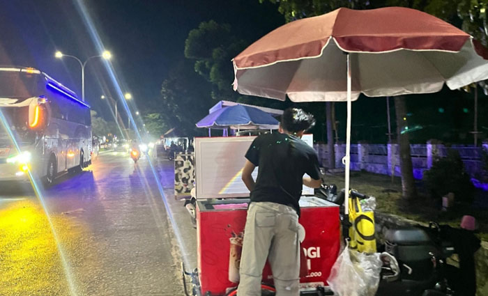 Nabil Febrianda (21) saat menjalankan usaha kopi gerobakannya di Jalan HR Soebrantas Panam, Ahad (1/3/2026) malam. 