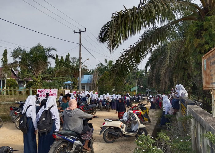 Siswa SMPN 2 Batang Peranap berdiri dan berkumpul di luar pagar sekolah akibat ada spanduk menutupi pintu pagar, Rabu (4/3/2026).