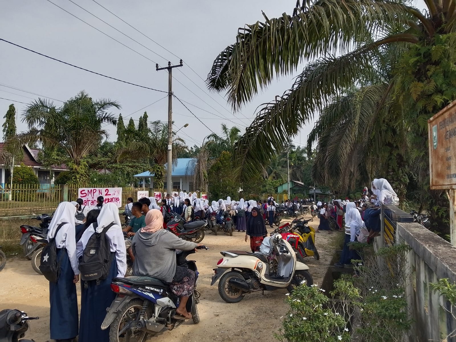 Pelajar SMPN 2 Batang Peranap berdiri dan berkumpul di luar pagar sekolah akibat ada spanduk menutupi pintu pagar, Rabu (4/3/2026).