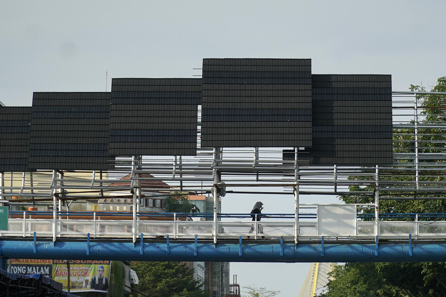 Warga berjalan di JPO Sukaramai Trade Center (STC) Pekanbaru, Jalan Jenderal Sudirman  yang tengah direvitalisasi dengan konsep atap bumbung khas Melayu, beberapa hari lalu.