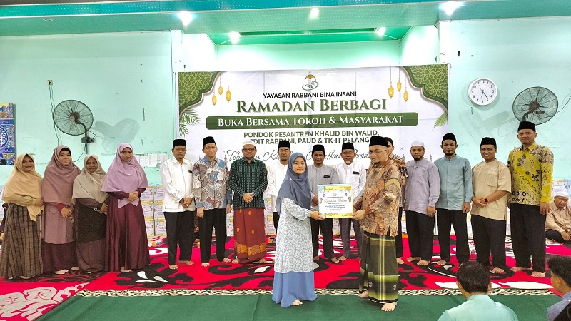 Penyerahan paket sembako secara simbolis dari Ketua YRBI H Roudhatul Firdaus LC MPd kepada Ketua Panitia Pelaksana Kegiatan Hj Elga Maharani LC, Ahad (8/3/2026).