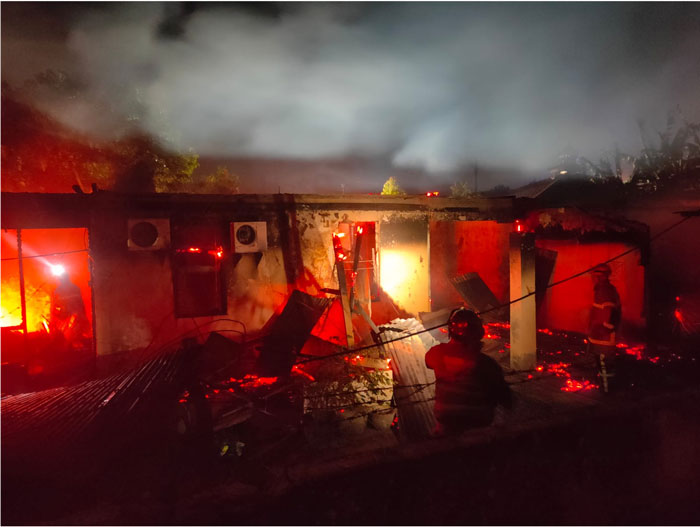 Petugas berusaha memadamkan api yang membakar rumah di kawasan asrama polisi Jalan Sisingamangaraja Pekanbaru, Kamis (12/3/2026) malam.