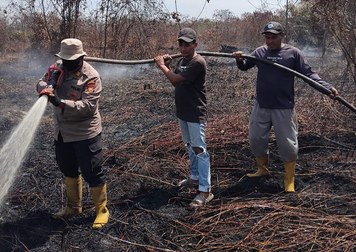 Kapolsek Rupat AKP Faisal melakukan pendinginan api Karhutla di Jalan Parit Jawa RT 004 RW 002 Dusun Sungai Mesim 2, Desa Sukarjo Mesim. Api sampai menembus desa tetangga, Kamis (12/3/2026).