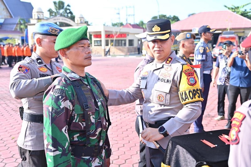 Kapolres Bengkalis AKBP Fahrian Saleh Siregar memasang pita kepada petugas gabungan dalam Apel Gelar Pasukan Operasi Ketupat Lancang Kuning di halaman Mako Polres Bengkalis, Kamis (12/3/2026).