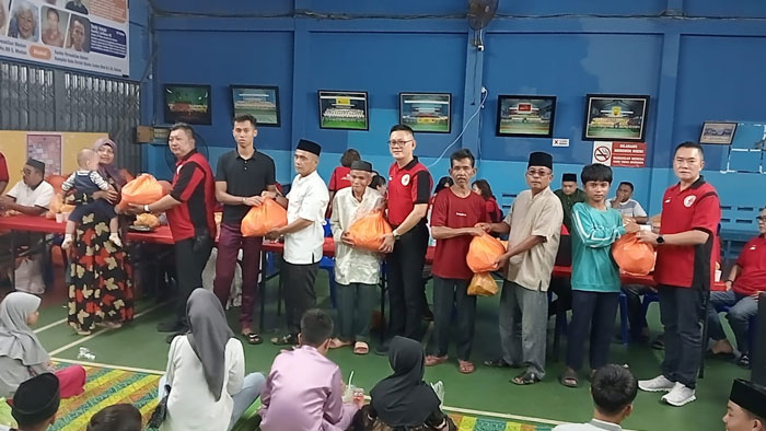 Ketua IKTS Pekanbaru Tohan (tengah) didampingi Ketua Harian IKTS Nata Hedy Nyo SE SH MH (dua kiri) foto bersama masyarakat saat menyerahkan bingkisan lebaran, Ahad (15/3/2026).