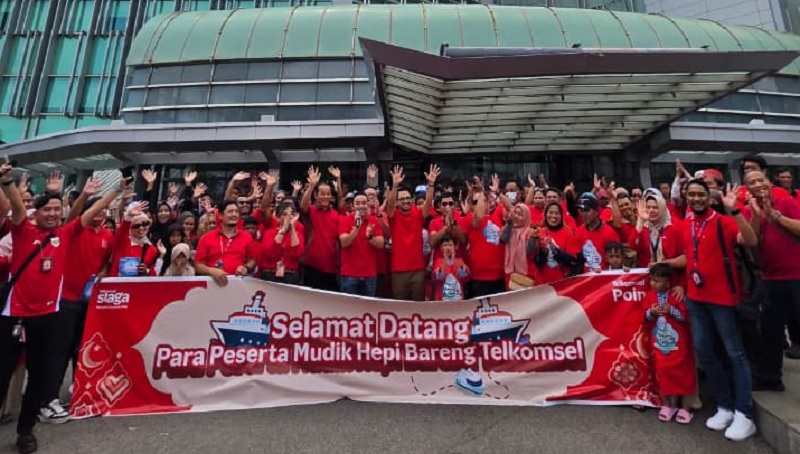 Jajaran manajemen Telkomsel foto bersama pelanggan yang ikut program mudik gratis.