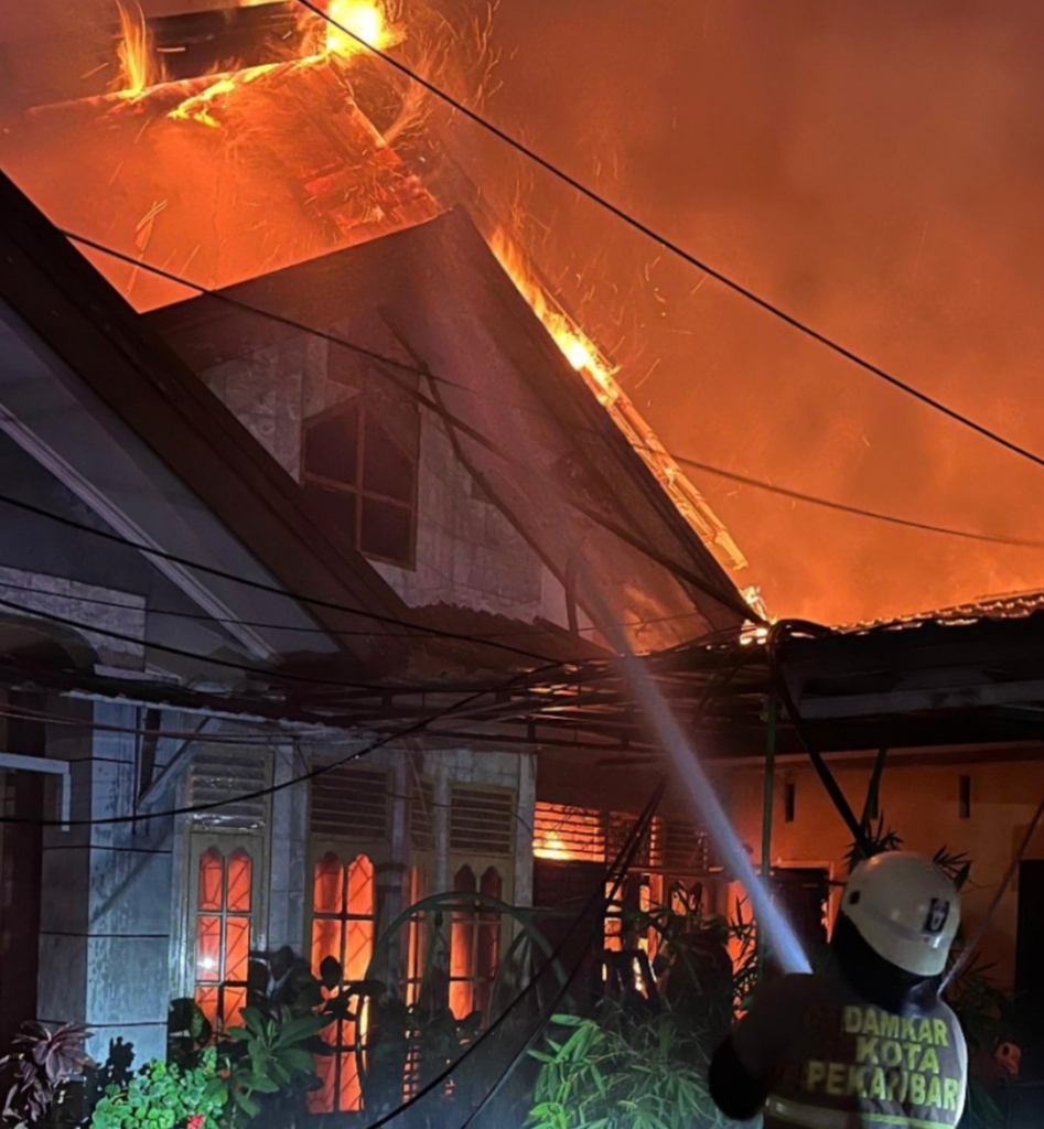 Petugas saat berupaya melakukan upaya pemadaman kios semi permanen serta satu unit rumah permanen di Jalan Adi Sucipto No. 295, Kelurahan Sidomulyo Timur, Marpoyan Damai, Sabtu (21/3/2026) dinihari.