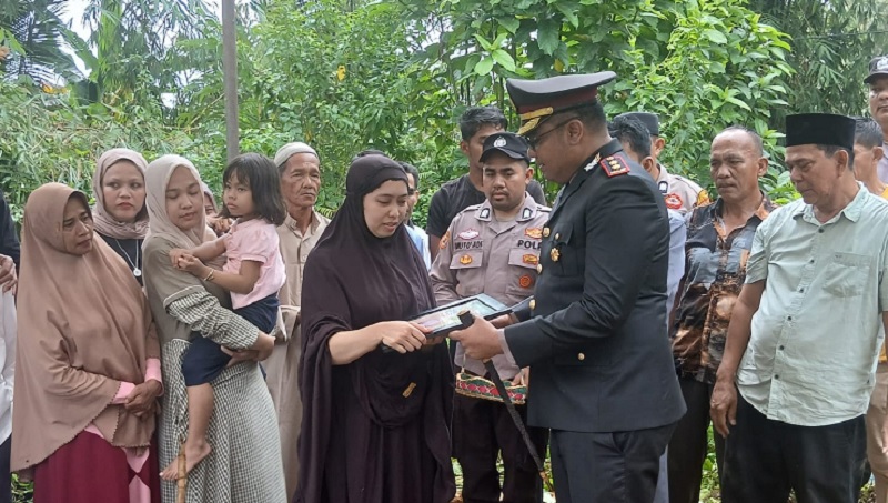Kapolres Kampar AKBP Bobby Putra Ramadhan S menyerahkan santunan kepada istri almarhum Aiptu Apendra, Sabtu (21/3/2026)