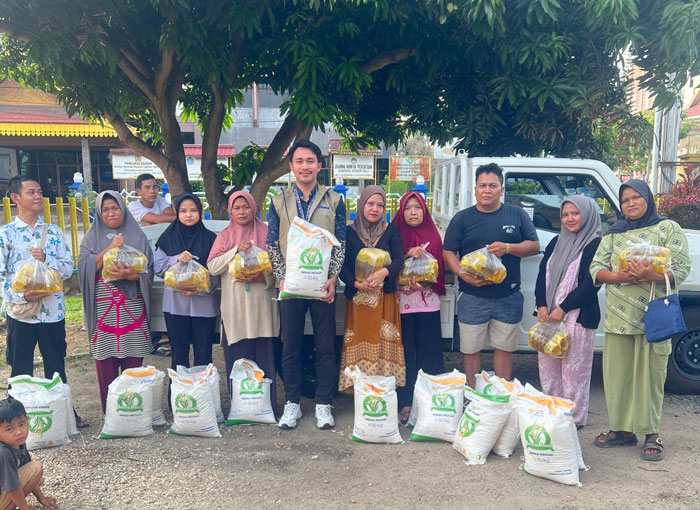 Karyawan Bulog Kantor Cabang Rengat (tengah) foto bersama dengan masyarakat penerima bantuan, Jumat (27/3/2026).