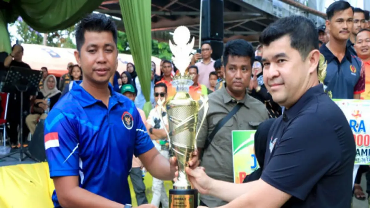 Pj Sekda Kampar Ardi Mardiansyah menyerahkan piala kepada Tim Srigala Muda dari Kecamatan Siak Hulu yang meraih juara pertama pada ajang Pacu Sampan dalam rangka HUT ke-76 Kabupaten Kampar, Ahad (5/4/2026). (Diskominfo Kampar untuk Riaupos.co)