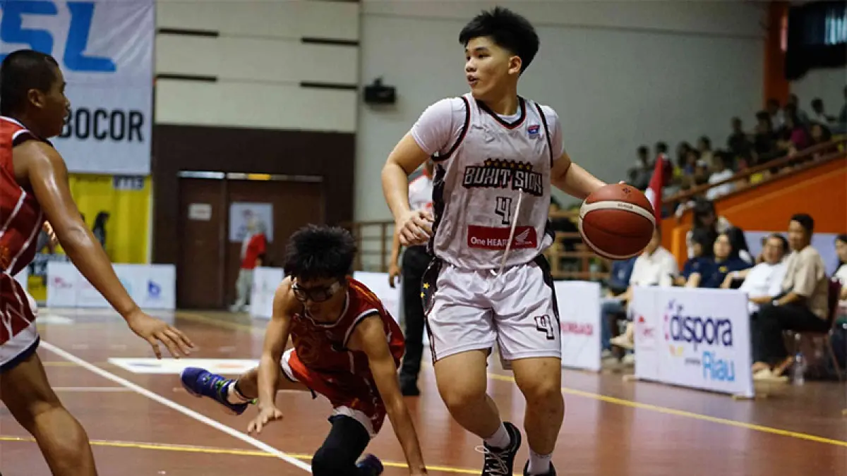 Pemain SMA Bukit Sion Jakarta (putih) berusaha melewati hadangan pemain SMK Unggul Sakti Jambi saat pertandingan Turnamen Rajawali Cup IV 2026 di GOR Tribuana Pekanbaru, Selasa (7/4/2026). ft EVAN GUNANZAR/RIAU POS
