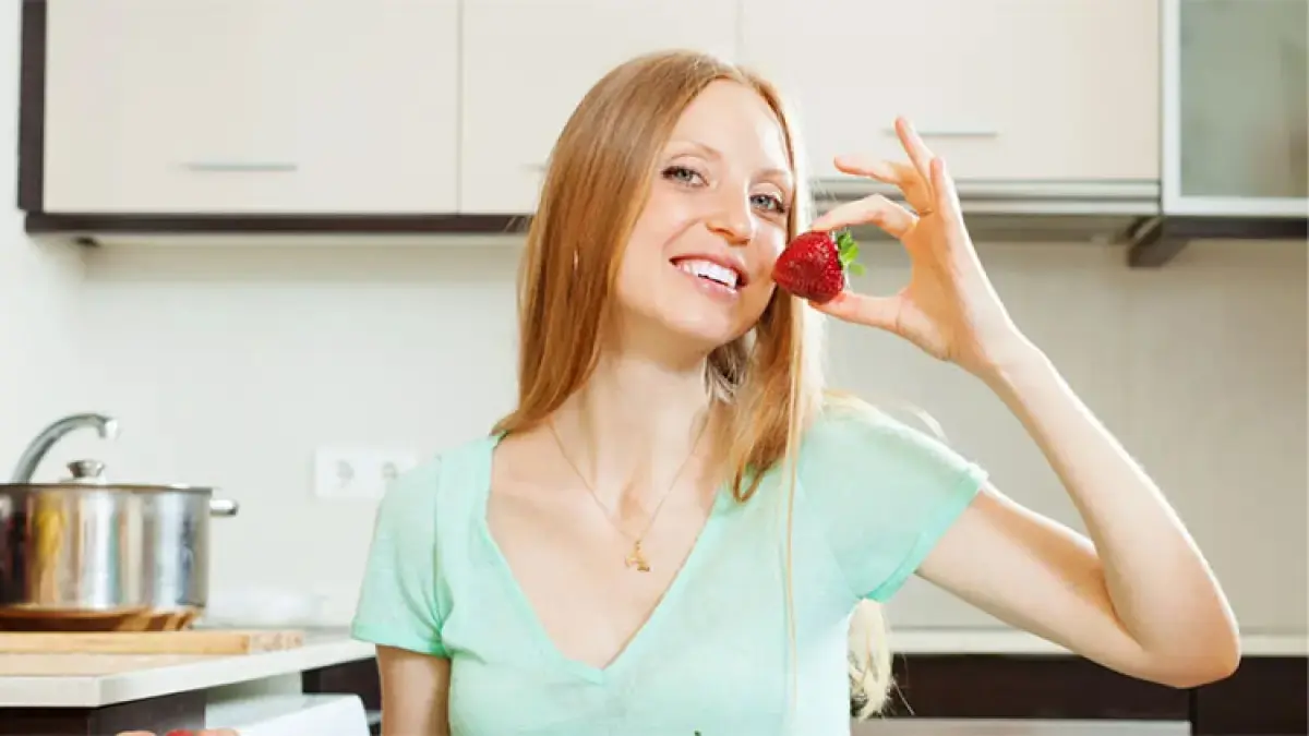 Seorang wanita sedang makan buah stroberi. Freepik

