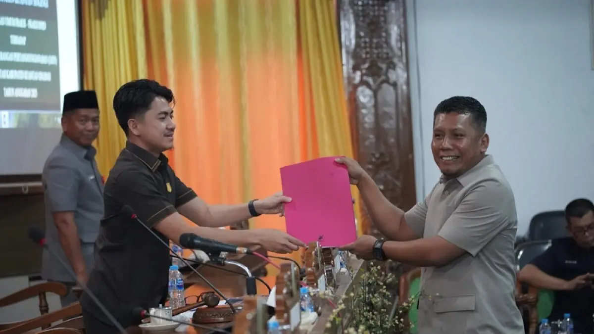 Juru bicara Fraksi Partai Gerindra Hardiamon menyerahkan pandangan umum fraksi terhadap LKPJ 2025 pada Wakil Ketua I DPRD Kuansing Satria Mandala Putra pada paripurna, Selasa (14/4/2026). (Desriandi Candra./Riaupos.co)