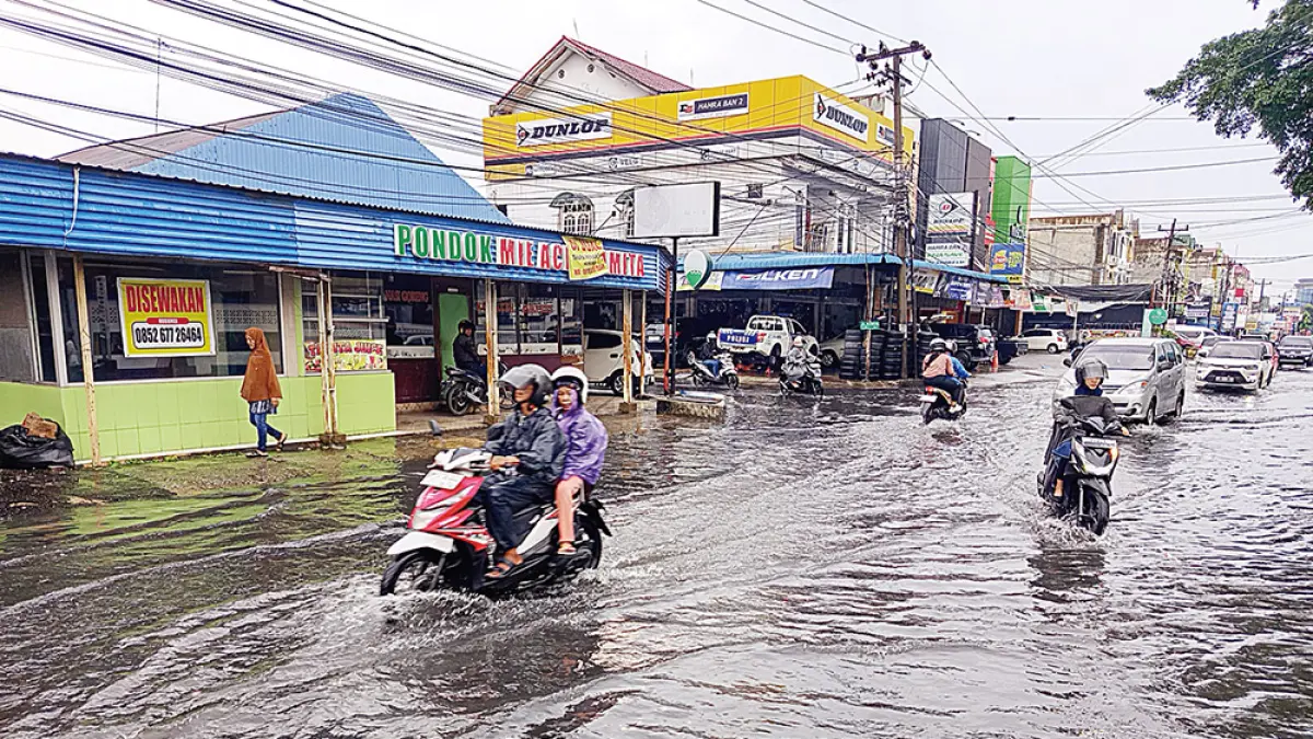 Pengendara melewati Jalan KH Ahmad Dahlan, Kecamatan Sukajadi yang  terendam air, Selasa (14/4/2026). Genangan ini dampak dari drainase yang tidak berfungsi dengan baik. (MHD AKHWAN)