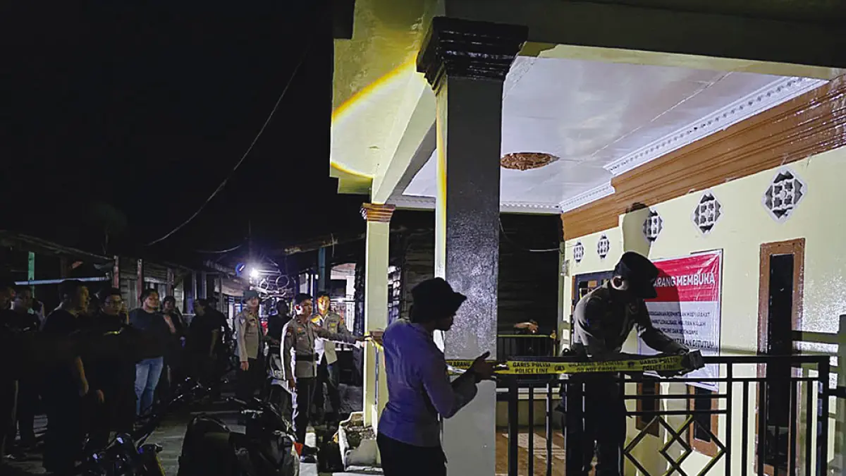 Personel Polres Rokan Hilir memasang garis polisi saat menyegel satu dari delapan rumah yang diduga milik pengedar dan bandar narkoba di Panipahan, Kecamatan Pasir Limau Kapas, Selasa (14/4/2026) malam. (Polres Rohil untuk Riau Pos)