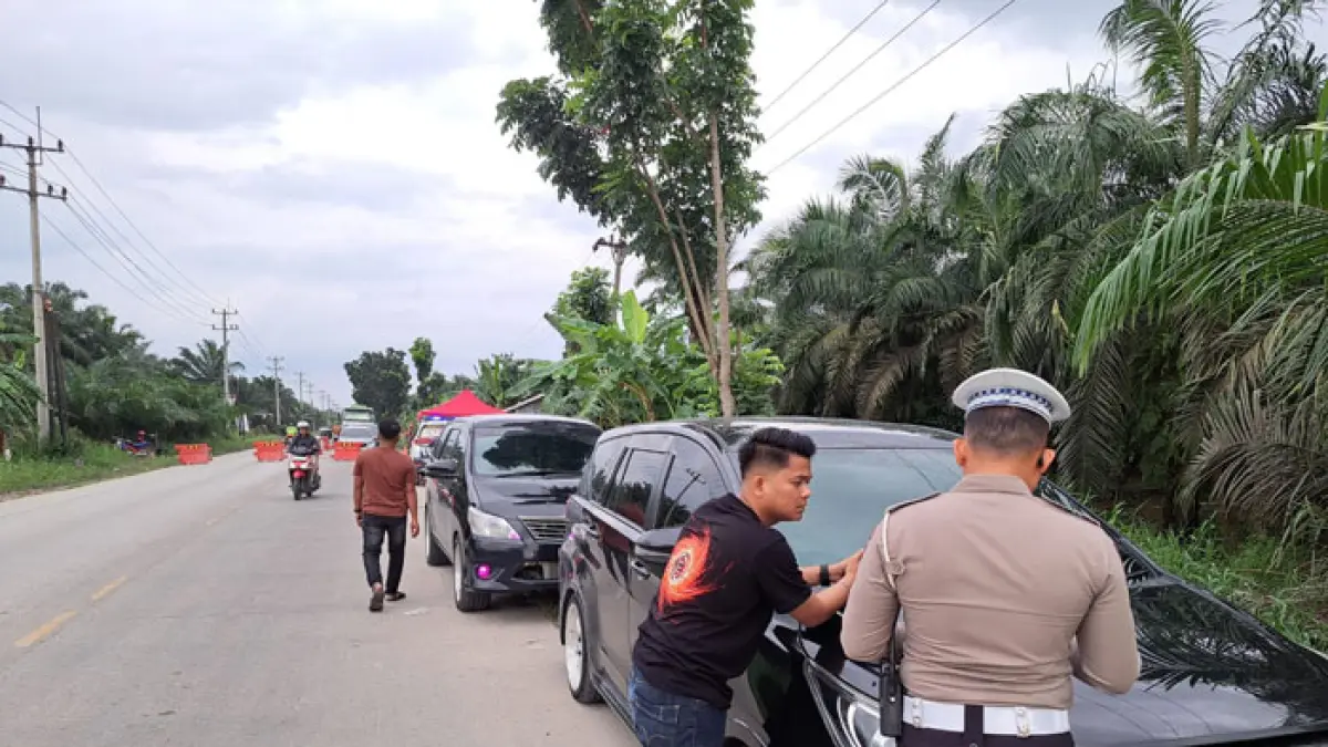 Personel Sat Lantas Polres Pelalawan menilang 2 pengemudi roda empat yang nekat menerobos antrean buka tutup jalan dampak pengerjaan penimbunan Jalintim KM 76, Kamis (16/4/2026). (Amin/Riaupos.co)