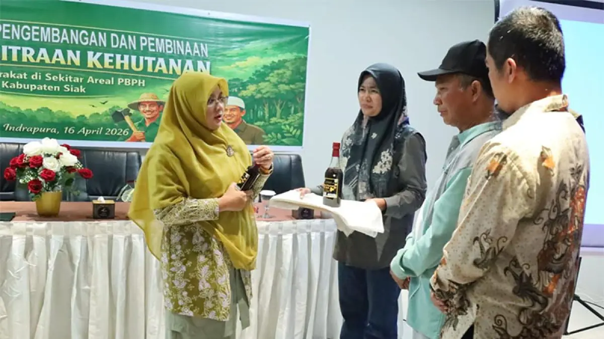 Bupati Siak Afni Z berbincang sambil memegang madu lebah produk KTH perhutanan sosial yang dikemas dengan baik di Kelurahan Kampung Rempak, Siak, Kamis (16/4/2026). (ISTIMEWA)