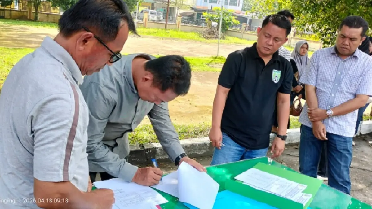 Plt Kepala Dinas Lingkungan Hidup Kuansing Delis Martoni menandatangani berita acara pelimpahan pengelolaan kebersihan dan pengelolaan sampah pada tiga kecamatan, Sabtu (18/4/2026) di halaman Kantor Camat Kuantan Tengah. (Desriandi Candra/Riaupos.co)