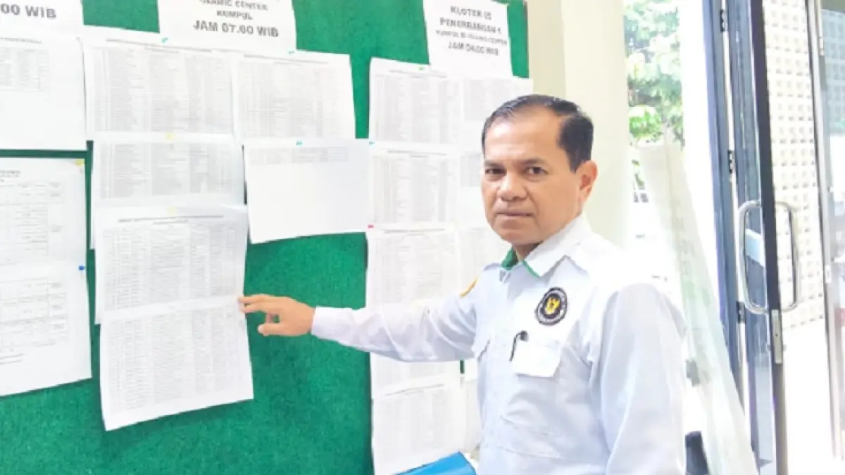 Kepala Kantor Kementerian Haji dan Umrah Kabupaten Kampar H Dirhamsyah memperlihatkan jadwal persiapan JCH Kabupaten Kampar di Kantor Kementerian Haji dan Umrah, Senin (20/4/2026). (Kemenhaj untuk Riaupos.co)