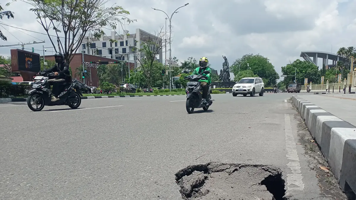 Kondisi badan jalan yang amblas hingga membentuk lubang di Jalan Jenderal Sudirman tepatnya di depan gerbang Kantor Gubernur Riau, Selasa (21/4/2026). (Dofi Iskandar/riau pos)
