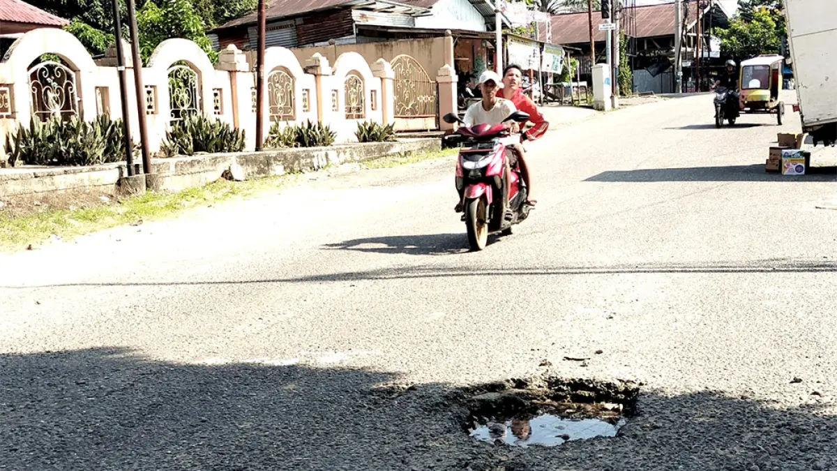 Pengendara roda dua terlihat ekstra hati-hati saat melintasi lubang yang dalam di ruas jalan Penganyoman Dusun Wonosri Barat, Desa Koto Tinggi, Kecamatan Rambah, Rohul, Selasa (28/4/2026). (ENGKI PRIMA PUTRA)
