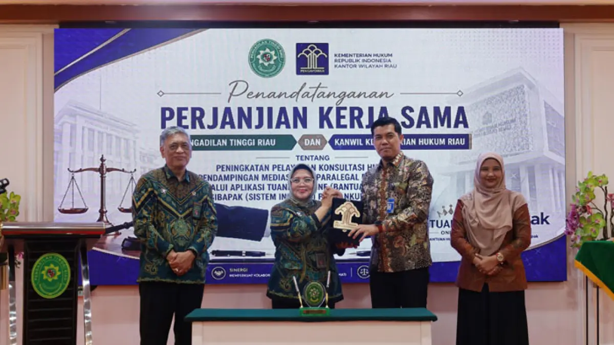Kepala Kanwil Kemenkum Riau Rudy Hendra Pakpahan menyerahkan cendramata kepada Ketua Pengadilan Tinggi Riau Diah Sulastri Dewi usia teken kerjasama, Kamis (30/4/2026). (Humas Kanwil Kemenkum Riau untuk Riaupos.co)