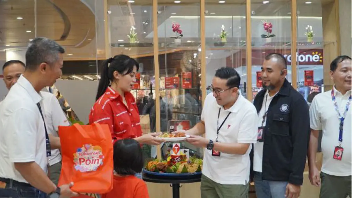 VP Consumer Business Area Sumatera Telkomsel, Saki H Bramono menyerahkan tumpeng kepada salah satu pelanggan yang datang ke Grapari Living World, baru-baru ini. (Telkomsel untuk Riaupos.co)