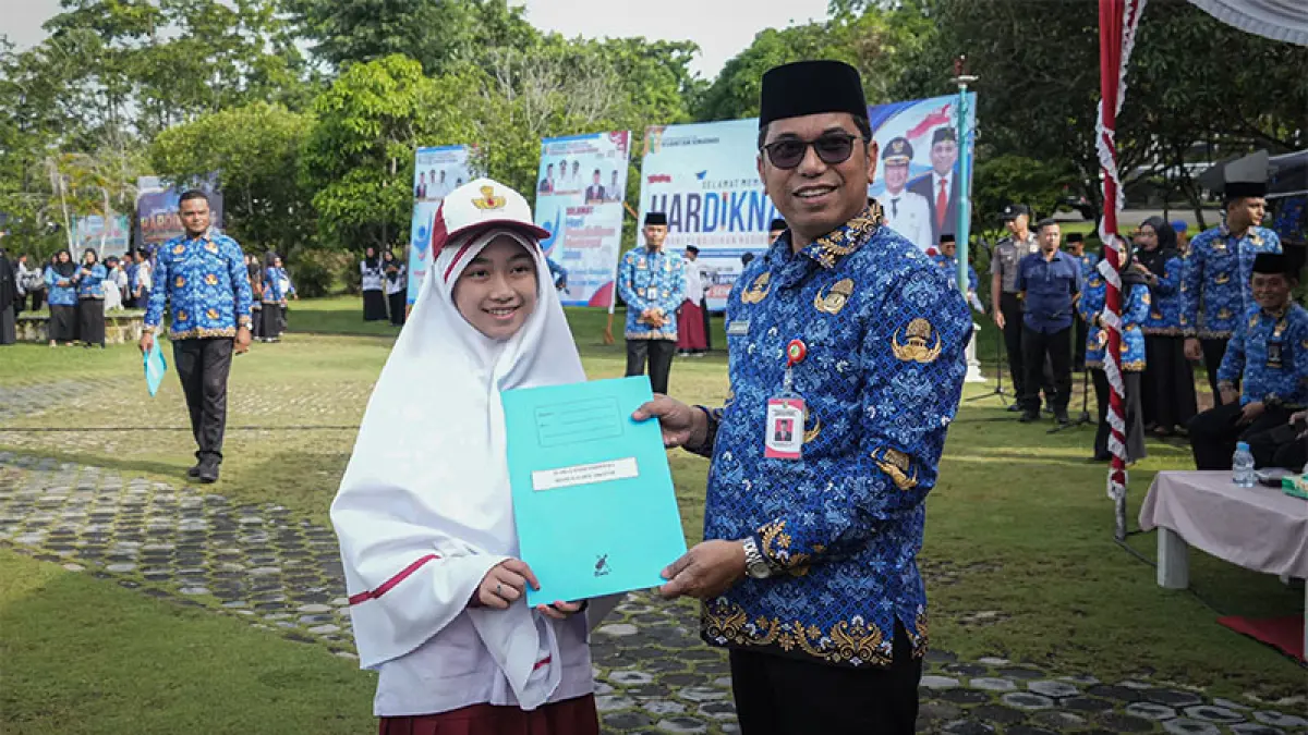 Sekda Kuansing Zulkarnain memberikan penghargaan pada Shanum, peraih Juara 2 Hafidz Indonesia 2026 di Peringatan Hardiknas, Senin (4/5/2026) di lapangan Komplek Perkantoran Pemkab Kuansing. (Desriandi Candra)