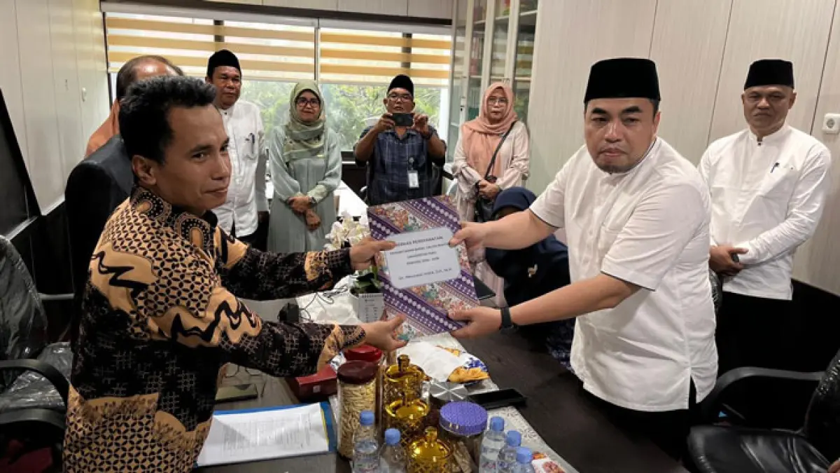 Dr Mexsasai Indra SH MH (kanan) saat menyerahkan berkas persyaratan pendaftaran bakal calon Rektor Unri kepada Ketua Panitia Pemilihan Rektor Dr HM Rasuli SE MSi Ak Ca ACPA, di Rektorat Unri Lantai 2, Jumat (8/5/2026). (Unri untuk Riaupos.co)