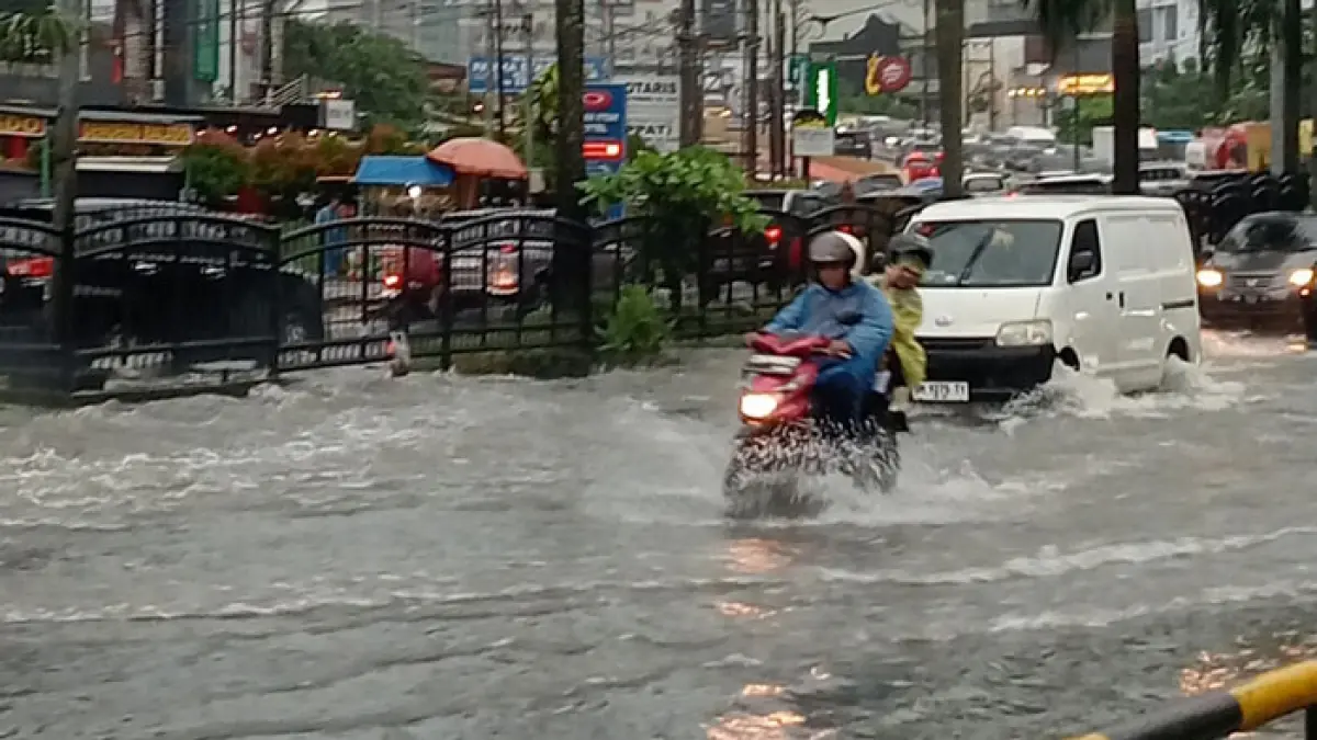 Pengendara motor dan mobil terlihat menerobos genangan air banjir di Jalan Jenderal Sudirman Pekanbaru, Jumat (8/5/2026). (Prapti Dwi Lestari/Riaupos.co)