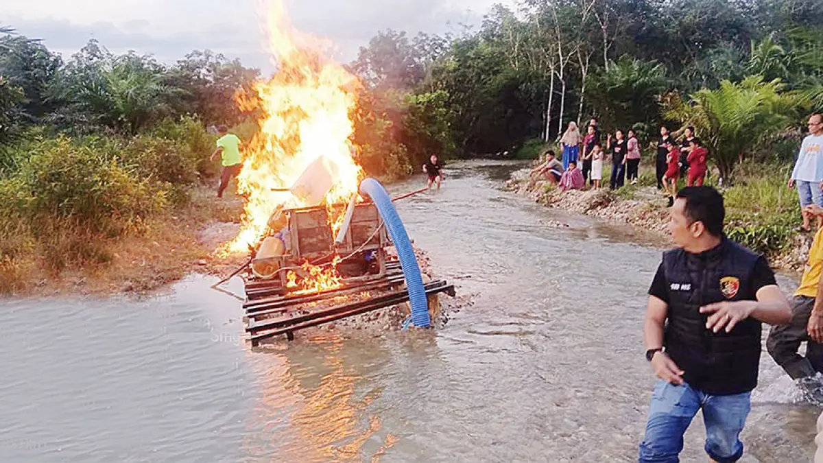 Personel Polsek Benai membakar satu rakit PETI stingkay yang ditemukan saat razia di daerah Kelurahan Beringin Jaya, Kecamatan Sentajo Raya, Ahad (10/5/2026) sore. (Polsek Benai untuk Riau Pos)
