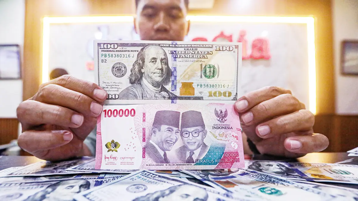 Karyawan menunjukan uang pecahan rupiah dan dolar Amerika Serikat (AS) di gerai penukaran mata uang asing Dolar Asia, Jakarta, Selasa (12/5/2026). (SALMAN TOYIBI)
